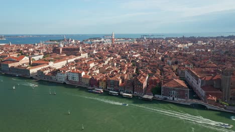 Venice,-italy-showcasing-the-historic-san-lazzaro-dei-mendicanti-and-bustling-water-traffic-on-a-clear-day,-aerial-view