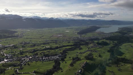 Panning-Drone-Shot-of-Glamorous-Mountainside-Village-with-Lake-in-Background,-Daytime-Switzerland