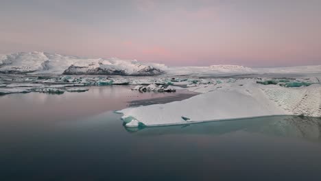 Cielo-Rosado-Del-Amanecer-Y-Icebergs-Que-Se-Reflejan-En-El-Lago-Glacial-Jokulsarlon