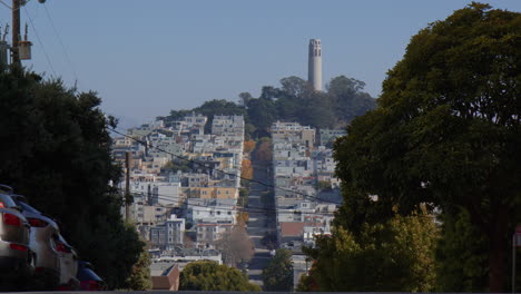 The-Crooked-Lombard-Street-with-Coit-Tower-Visible-in-the-Distance-in-San-Francisco,-California---Wide-Shot
