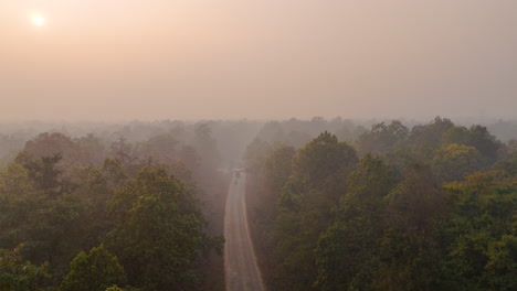 Smoke-and-foggy-view-of-East-Nepal-Terai-region,-Drone-shot-of-Landscape-revealing-wild-forest-with-transportation-4K