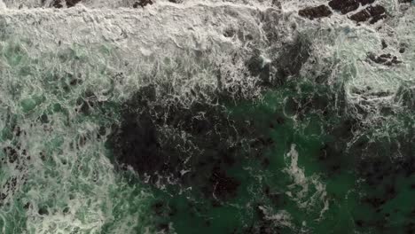 Langsam-Absteigende-Luftaufnahme-Von-Meereswellen,-Die-In-Mit-Bambus-Bedeckten-Gewässern-über-Den-Rahmen-Rollen,-Und-Sichtbaren-Felsbrocken