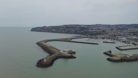 Cinematic-aerial-orbit-of-Howth-harbour,-focusing-on-the-lighthouse