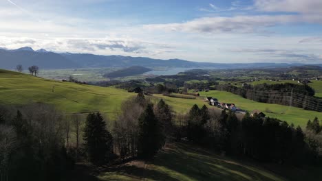 Malerische-Schwenk-Drohnenaufnahme-Eines-Kleinen-Dorfes-Im-Hangtal-Mit-Bergigem-Hintergrund,-Schweiz