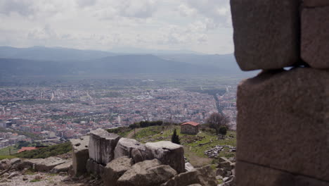 Eine-Steinmauer-Im-Vordergrund-Mit-Einer-Stadt-Und-Bergen-Im-Hintergrund-In-Pergamon