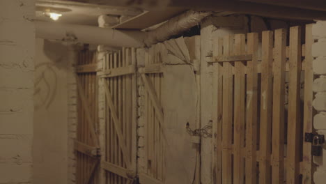 Ein-Korridor,-Der-Von-Mehreren-Hölzernen-Gittertoren-Flankiert-Wird,-Was-An-Ein-Verlies-Oder-Eine-Historische-Gefängnisatmosphäre-Erinnert