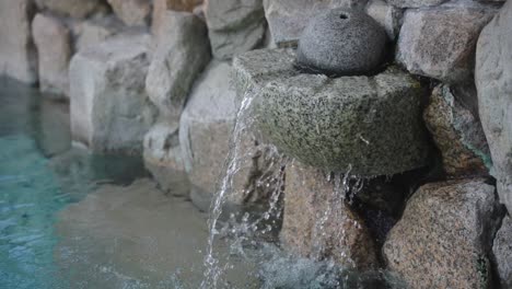 Cámara-Lenta-Inclinada-Hacia-Abajo-Desde-Una-Fuente-De-Agua-Mineral-Caliente-En-Un-Baño-Onsen-Japonés