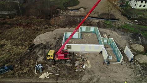 Aerial-shot-of-a-house-under-construction-with-crane-and-workers-surrounded-by-nature-and-trees