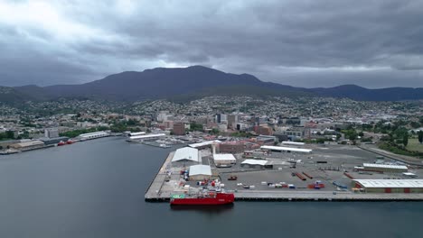 Small-Red-ship-Tasmania-Hobart-docks-helicopter-pas-mountain-overcast-high-drone-50fps