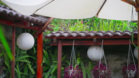 Raindrops-Grace-a-Wooden-Roof-and-Lantern-in-a-Garden-Oasis,-Captured-in-Slow-Motion