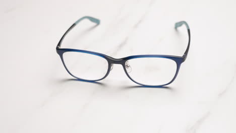 Verkleinern-Sie-Die-Blaue-Korrektionsbrille-Auf-Dem-Tisch-In-Heller-Farbe