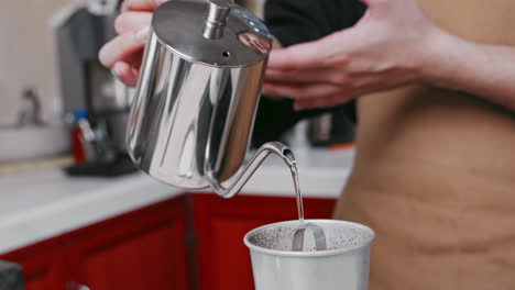 Erfahrener-Barista-Gießt-Fachmännisch-Wasser-Aus-Einem-Metallkessel-In-Einen-Kaffeebehälter-Für-Die-Perfekte-Tasse