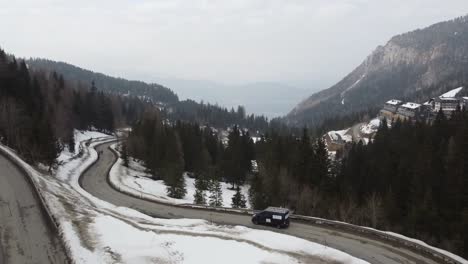 a-maintenance-van-with-ad-and-ladder-on-top-driving-on-snowy-twisted-roads-in-mountains