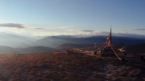 Tibet-Mongolian-sacred-temple-strewn-with-prayer-flags-overlook-sunrays-on-valley,-Xingduqiao-Yuzixi-Yala-Gongga-aerial-orbit