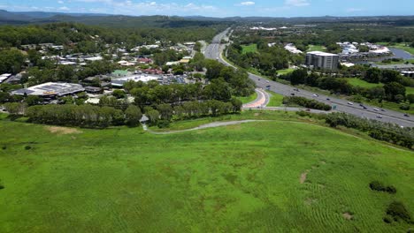 Forward-moving-aerial-over-Firth-park,-Mudgeeraba-Market-Shopping-centre-and-M1,-Gold-Coast,-Queensland,-Australia