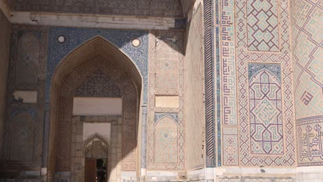 bright-sunlight-hitting-islamic-tiling-and-artwork-on-arched-doorway-in-registan-square-in-Samarkand,-Uzbekistan-along-the-historic-Silk-Road