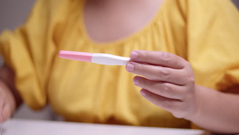 Detail-Einer-Frau-Im-Gelben-Kleid,-Die-Zusammen-Mit-Dem-Kalender-Den-Schwangerschaftstest-überprüft