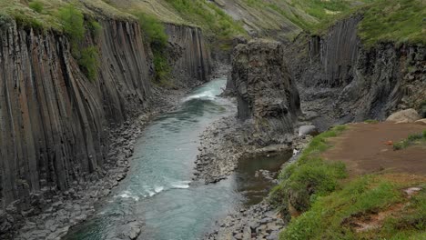 Stuðlagil-Basalt-formations-cradle-a-tranquil-blue-river's-flow