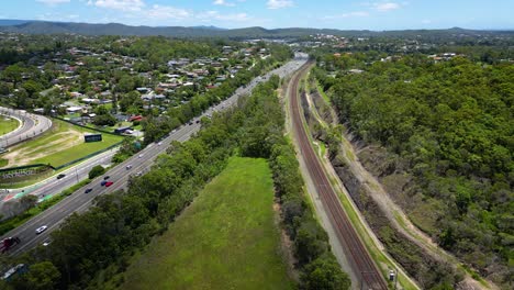 Reversing-aerial-view-over-Worongary,-M1-and-rail-line-near-Skyridge-development,-Gold-Coast,-Queensland,-Australia