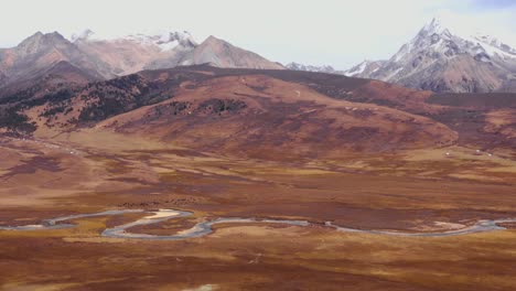 Sichuan-Genyen-or-Genie-grassland-holy-mountains-of-Tibetan-China-with-meandering-river-below-snowy-mountains