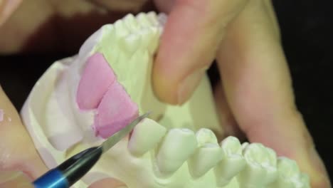 artistic-dental-laboratory-technician-carving-teeth-anatomy-on-cast,-close-up