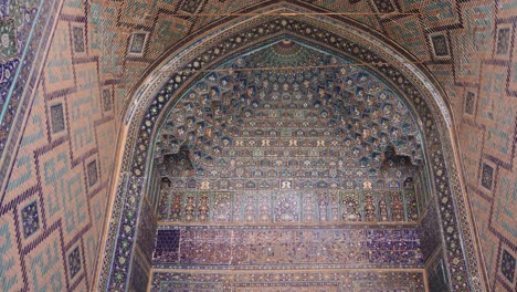 detailed-blue-tiling-on-historic-archway-entering-a-traditional-mosque-in-registan-square-in-Samarkand,-Uzbekistan-along-the-historic-Silk-Road