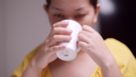 Holding-a-ceramic-mug-as-the-woman-is-sipping-some-hot-beverage-while-closing-her-eyes-as-she-savors-what-she-is-drinking