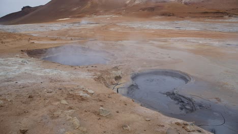 Dampfend-Heiße-Geothermale-Schlammbecken-In-Der-Rauen-Isländischen-Landschaft