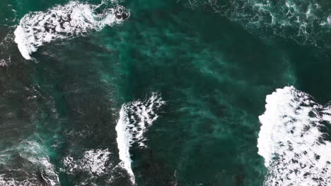 drone-pull-up-shot-of-large-and-powerful-waves-crashing-down-on-the-surfers-trying-to-catch-the-waves