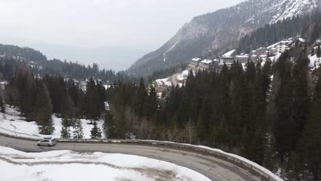 silver-family-car-van-with-roof-box-driving-on-snowy-twisted-roads-in-winter-mountains