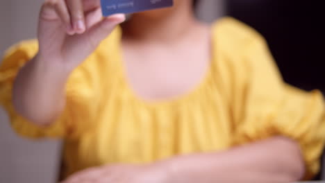 A-woman-showing-a-close-up-shot-of-a-credit-card-that-she-is-holding-with-her-fingers-on-her-right-hand