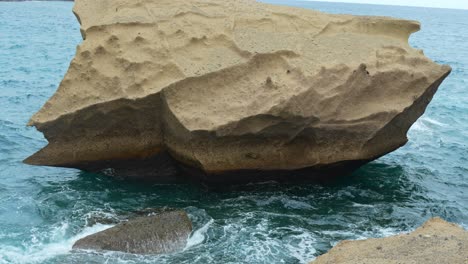 Tilt-up-view,-massive-sharp-sandstone-cliff-located-in-middle-of-ocean