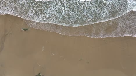 Aerial-View-Over-Foamy-Waves-Of-The-Sea-Running-Onto-A-Sandy-Beach---Drone-Shot