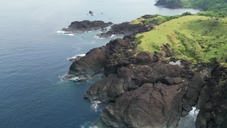 Picturesque-aerial-orbit-of-coastal-rocky-cliffs-facing-turquoise-ocean-cove