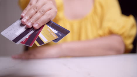 Woman-in-yellow-dress-presenting-her-various-credit-cards-to-the-camera