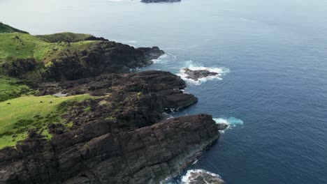 Rocky-cliffs-and-green-fields-by-the-sea-at-puraran-baras,-tranquil-and-picturesque,-aerial-view