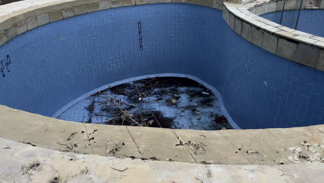 Dirt-At-Bottom-Of-Abandoned-Dilapidated-Empty-Pool,-High-Angle-View