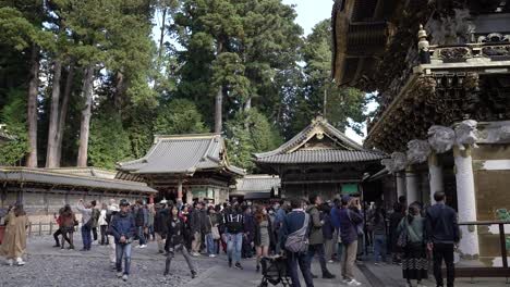 Crowded-Line-Of-Tourists-Making-Their-Way-Out-Through-The-Courtyard-Of-Nikko-Toshogu-With-Kagura-den-And-Ritual-Hall-In-Background