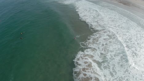 Aerial-forward-view-of-swimmers-in-the-sea-with-wave-foam-effect