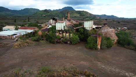 zoom-of-koloa-sugar-mill-with-mountains-in-background,-drone-aerial