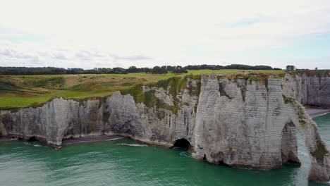 Flying-towards-the-land,-next-to-the-rocky-arch-of-Etretat-in-France