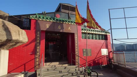 Profile-view-of-architecture-of-Tin-Hau-Temple-with-flags-waving-during-a-clear-sunny-day-in-Lei-Yue-Mun,-Hong-Kong
