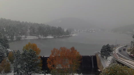 Downtown-Evergreen-Lake-dam-American-flag-Colorado-historic-downtown-aerial-drone-blizzard-fall-autumn-winter-first-snowfall-colorful-aspen-trees-Rocky-Mountain-front-range-Denver-right-circle-motion