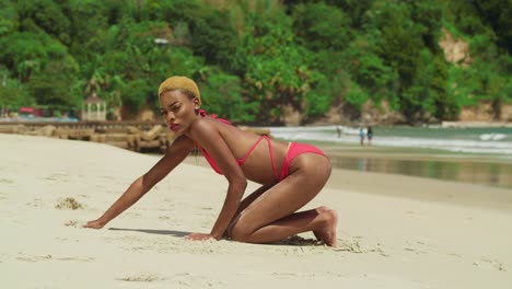 A-black-girl-in-a-vibrant-red-bikini-adds-a-touch-of-elegance-to-a-tropical-white-sand-beach-in-the-Caribbean-kneel-in-the-sand