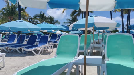 Relax-in-Caribbean-style:-Empty-beach-chairs-and-umbrellas-adorn-the-sandy-shores-against-the-backdrop-of-azure-waters-and-skies,-epitomizing-tropical-tranquility