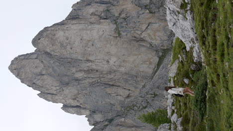 VERTICAL-Carefree-woman-hiking-under-Dolomites-mountain-peak-in-Ra-Gusela,-Italy