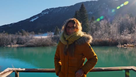 4K-video-of-a-happy-young-caucasian-female-standing-near-the-lake-in-the-natural-reserve---Zelenci,-Slovenia