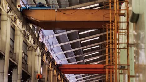 Ladder-to-climb-on-a-large-machine-in-the-factory-production-area-with-view-of-moving-overhead-crane