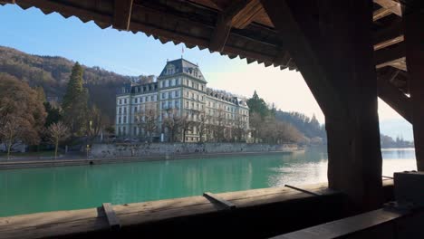 Viewing-beautiful-building-by-river-from-slit-in-covered-bridge,-Thun