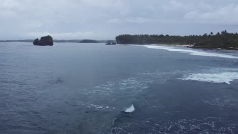 Flying-low-over-sea-waves-crashing-on-tropical-shore-on-cloudy-day